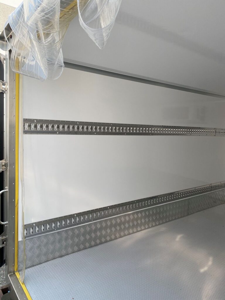 Rear of 2026 NEW Govi 7′ x 16′ Seamless trailer with rear doors open, plastic insulation flaps pulled aside showing interior of trailer left side.